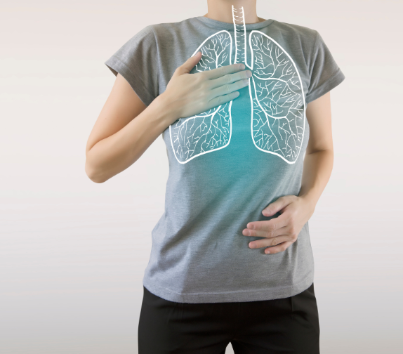 a woman in a grey t-shirt puts her hand on her heart over a white outline of her lungs