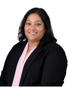 A headshot of Nidhi in a black blazer with a white background
