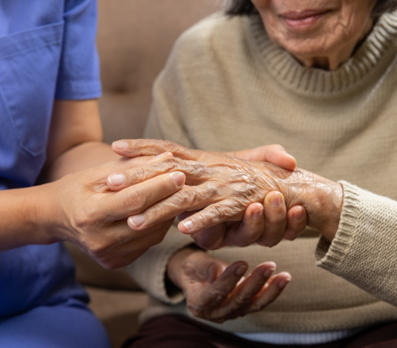 a person in scrubs holds the hand of an elderly person, holding a knuckle between their fingers