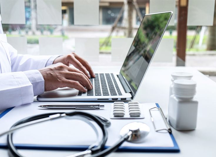 a physician types at their computer