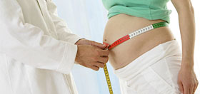 Physician measuring pregnant woman's belly